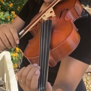 Uma menina violinista da Orquestra Jovem Theatro São Pedro segura o violino com as mãos em posição como se estivesse tocando.